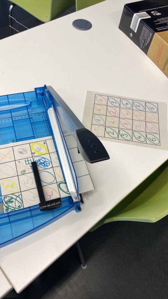 Handgemalte Karten auf DIN A4 Papier werden mit einem Schneidegerät geschnitten